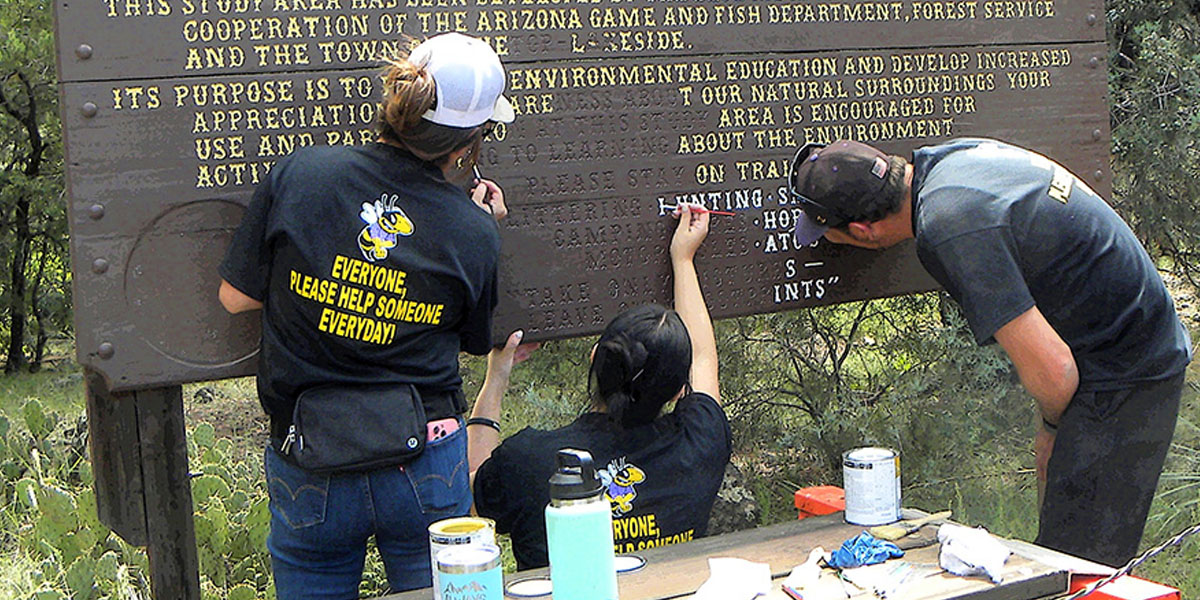 Volunteers painting older sign
